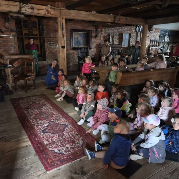 Dzieci siedzą na ziemi, oglądają bajkę o zwyczajach w średniowieczu